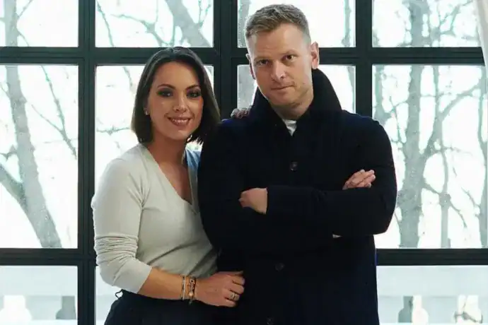 Nő és férfi portréja modern környezetben, háttérben nagy ablakok és téli táj.